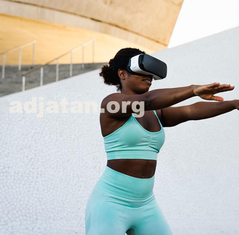 Happy fit African woman using futuristic virtual reality glasses during training session